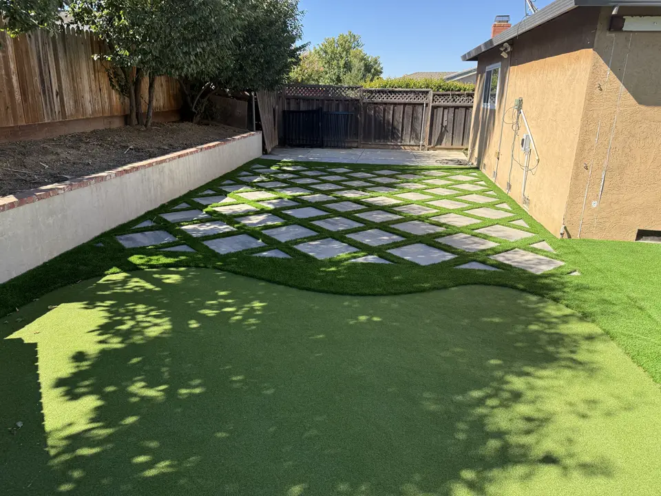Diamond pattern of concrete pavers set in artificial turf in a side yard