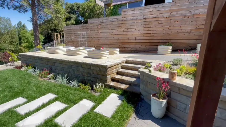 Concrete stepping pads crossing a lawn below a terraced wall