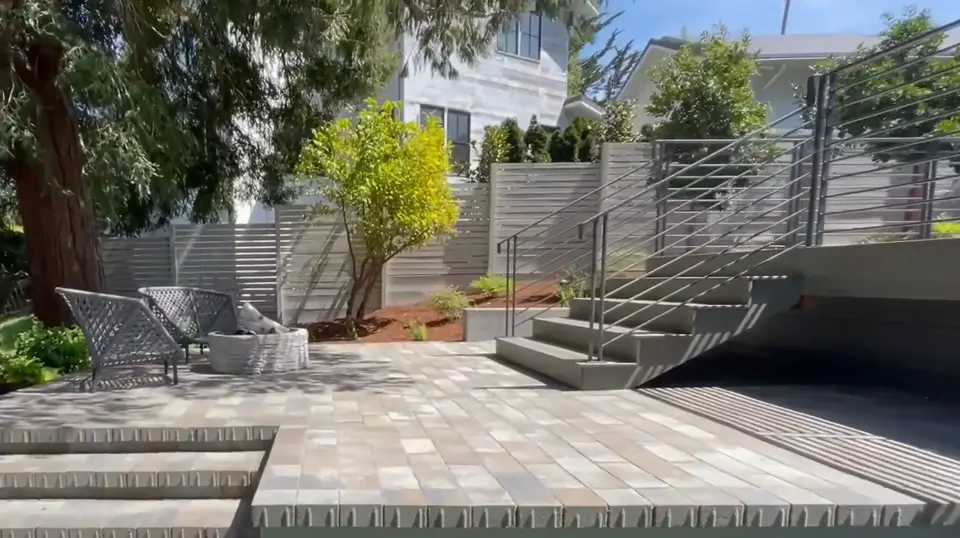 Gray paver patio with wide steps and a metal railing